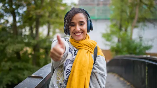 Junge Frau auf einer Brcke, die den Daumen hochstreckt.