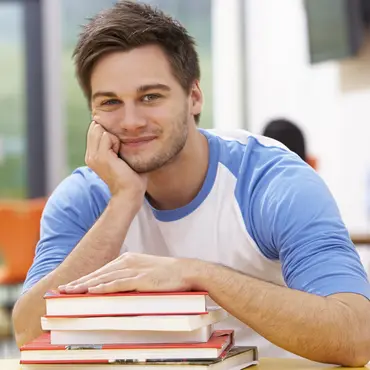 Male Student Studying In Classroom With Books