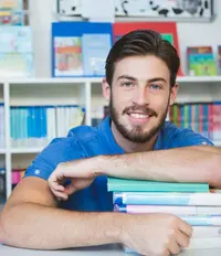 Lehrer sitzt mit Bchern in der Bibliothek